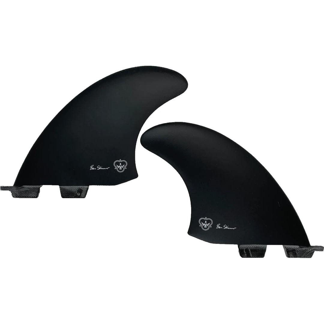 Two black surfboard fins, signed by Ben Skinner, on a white background