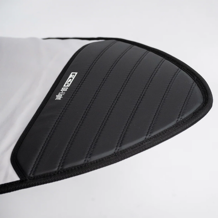 Close-up of a black FCS padded surfboard nose-cover on a white background.