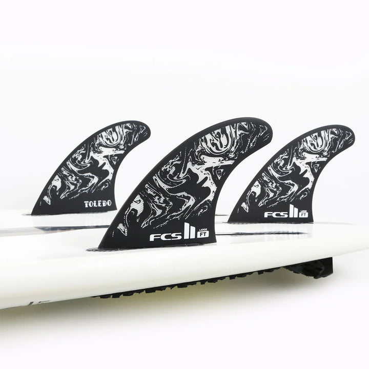 Close-up of a surfboard with three fins on a white background