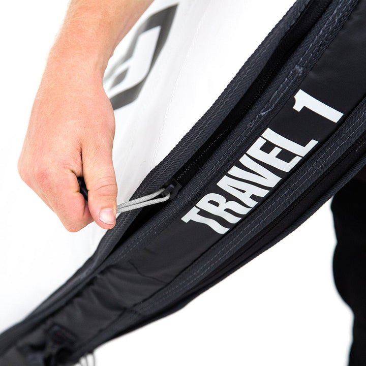 Close-up of person opening a black FCS surfboard bag with &