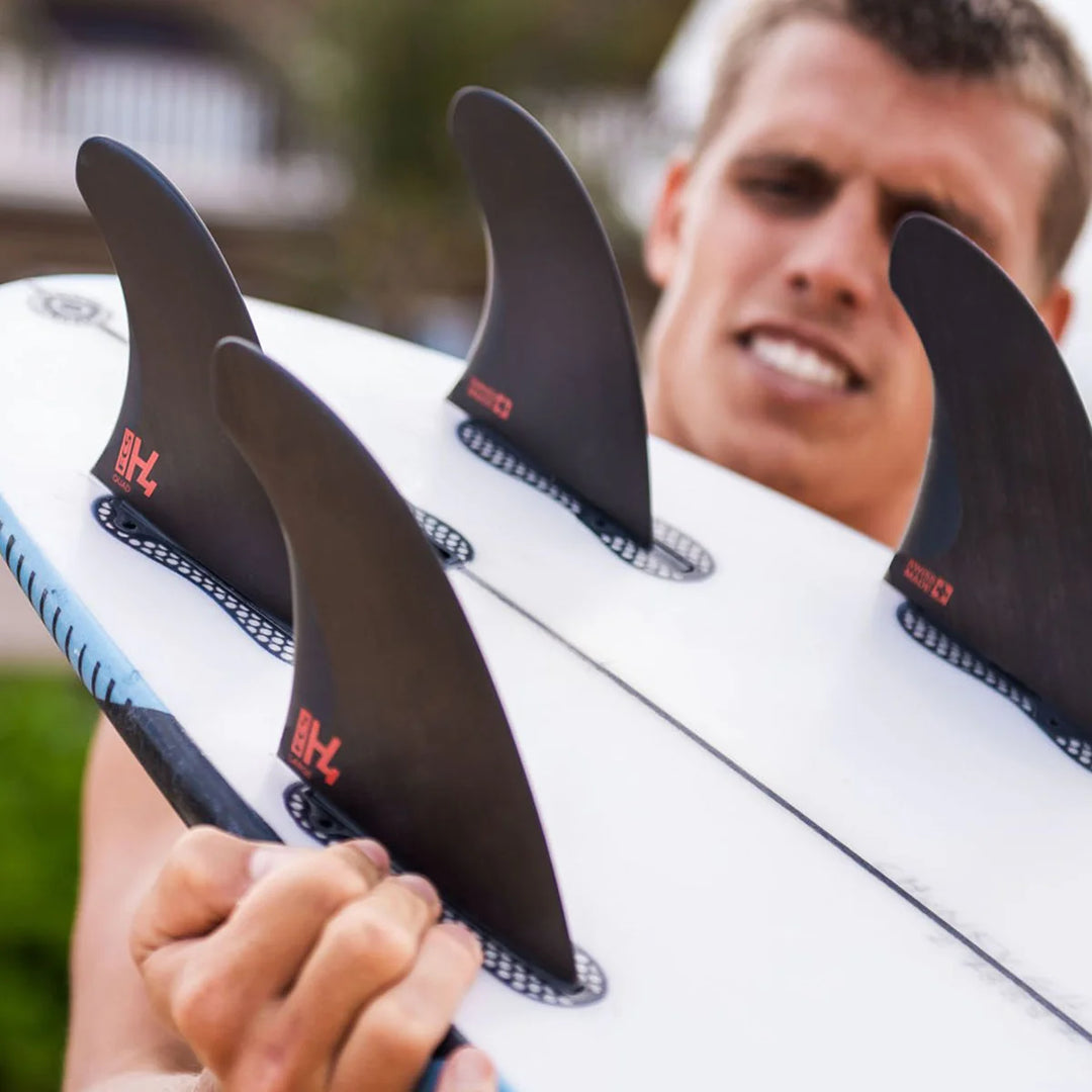 Person holding a surfboard with fins, blurred background