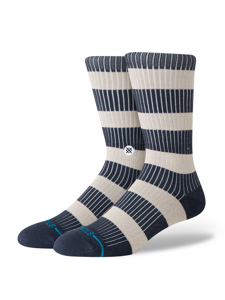 A pair of striped crew socks in navy and beige, with a blue stripe and STANCE logo across the toes, on a white background.