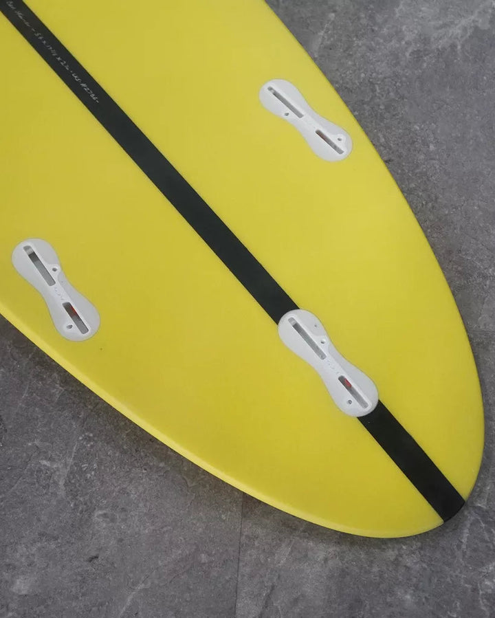 Yellow surfboard with black stripe on a grey surface