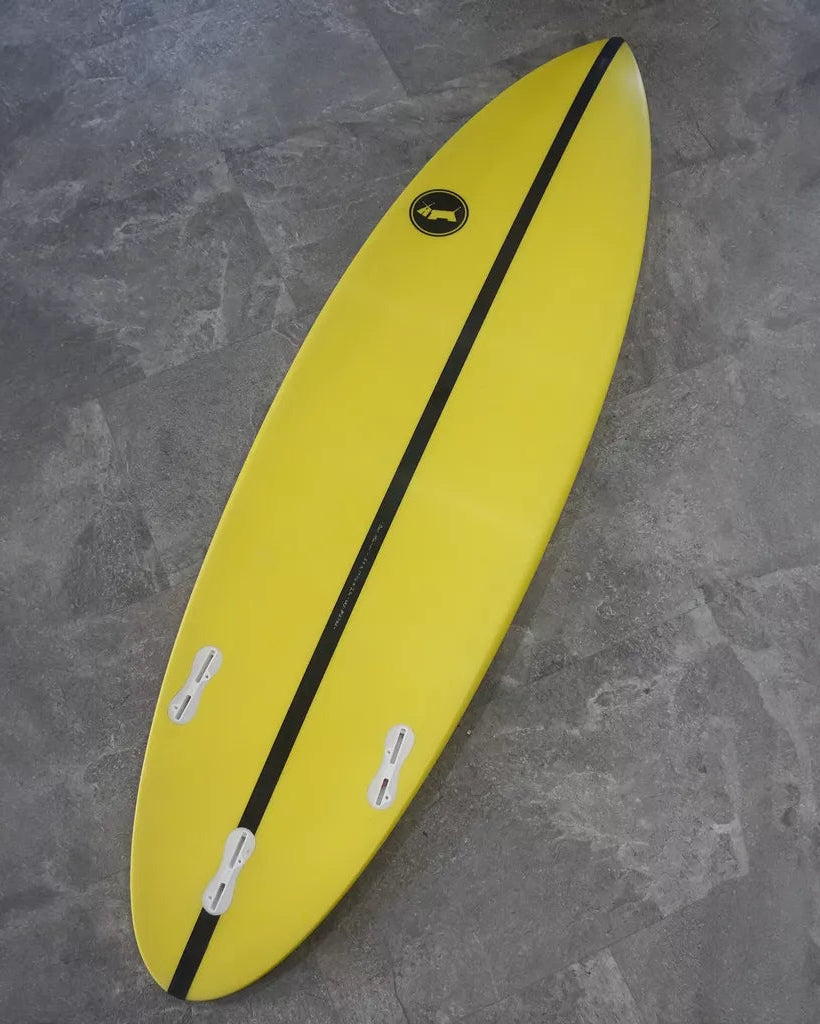 Yellow surfboard with a black stripe on a grey stone surface