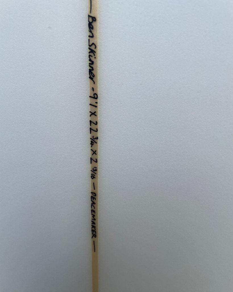 Wooden surfboard stringer with measurements and branding on a white background