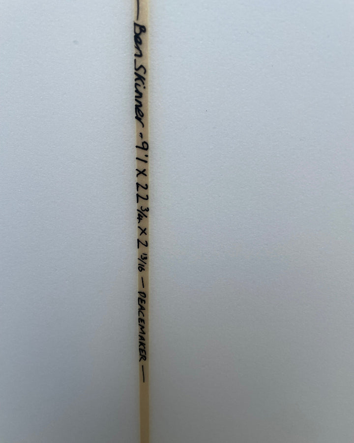 Wooden surfboard stringer with measurements and branding on a white background