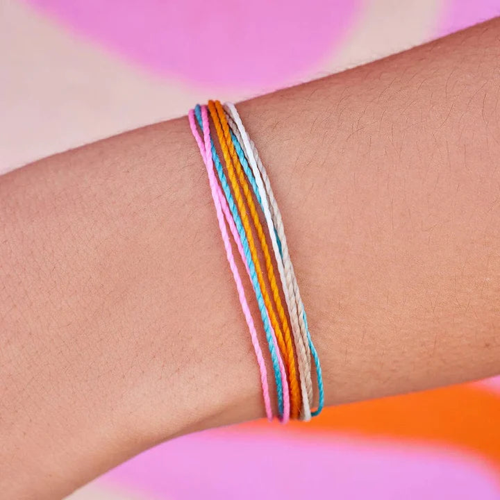Multicolored bracelets on a wrist with a colorful background