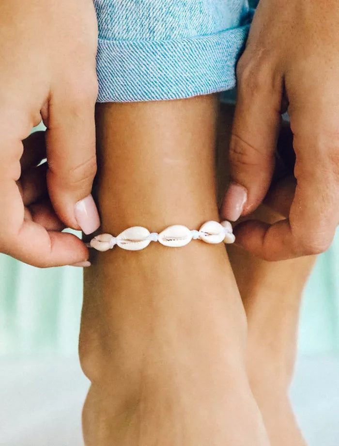 Person wearing a shell anklet on a blurred background