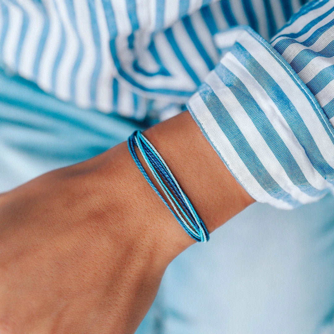 Close-up of a wrist with blue bracelets against a blurred background