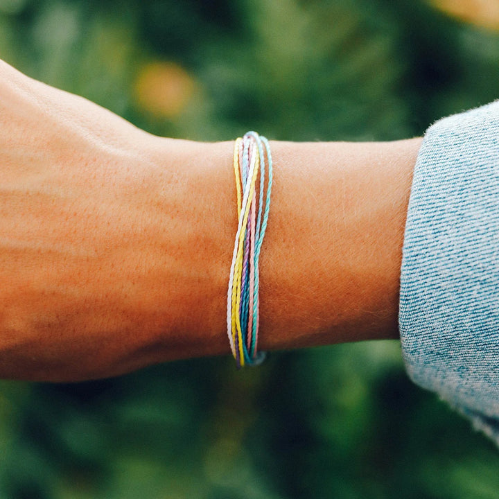 Close-up of a wrist wearing a colorful bracelet with a blurred green background
