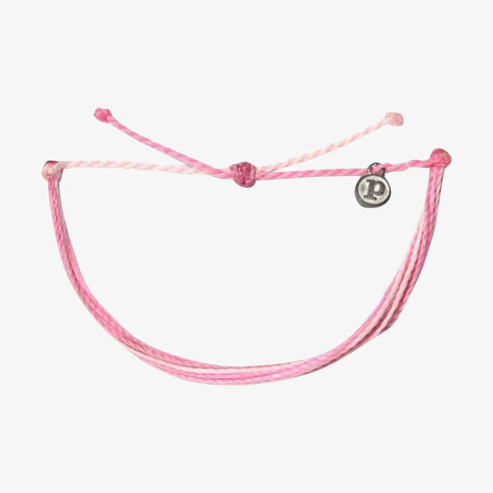 Pink bracelet with a small round charm on a white background