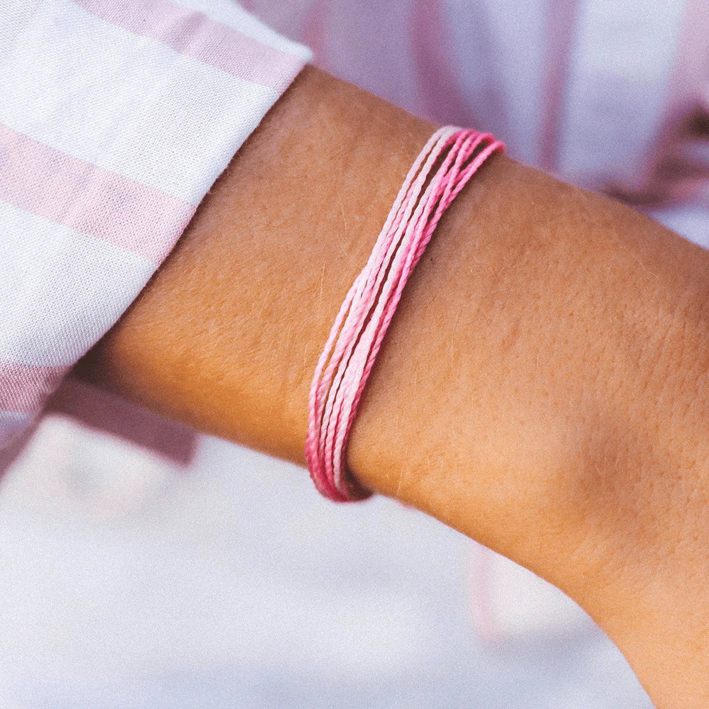Close-up of a wrist wearing a pink bracelet with a blurred background