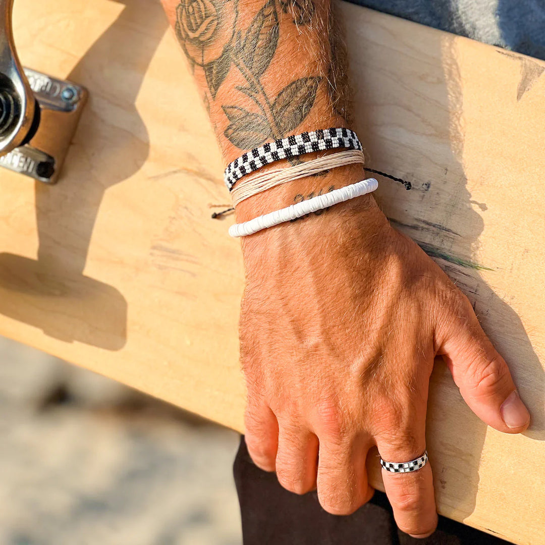 Hand with tattoos and bracelets holding a skateboard