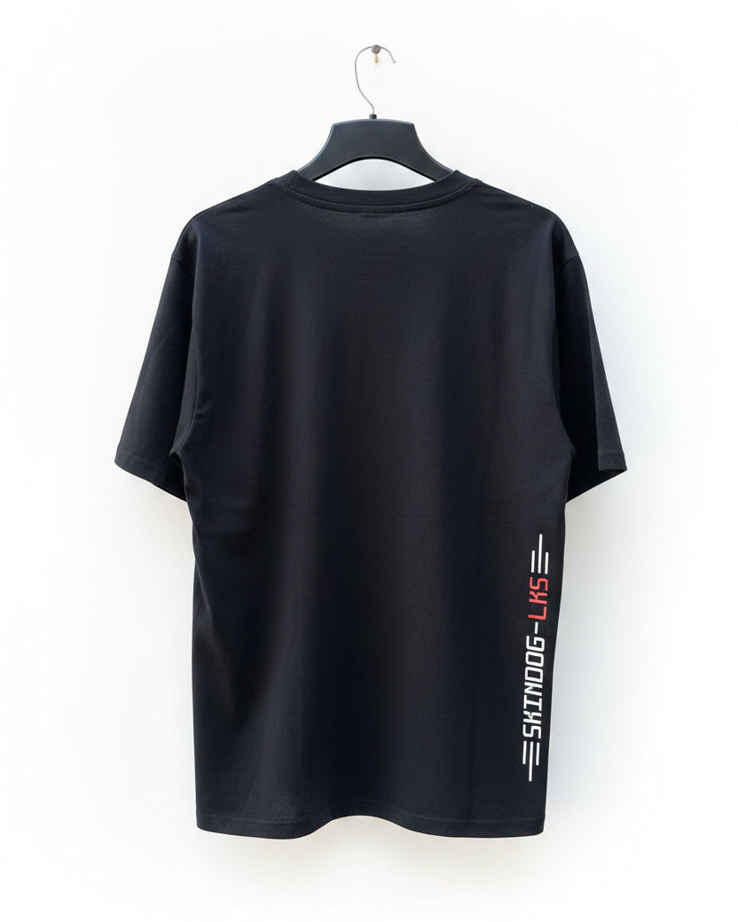 A black short-sleeve t-shirt hanging on a black hanger against a white background. The shirt features a vertical graphic on the lower left side with the text 'SKINDOG-LKS' in white and red.
