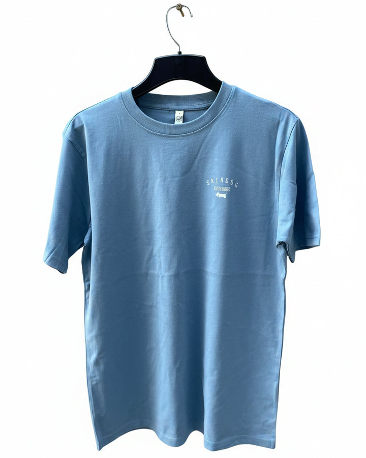 A light blue crewneck t-shirt hanging on a black hanger against a white background. The shirt features a small white graphic on the left chest with the text &