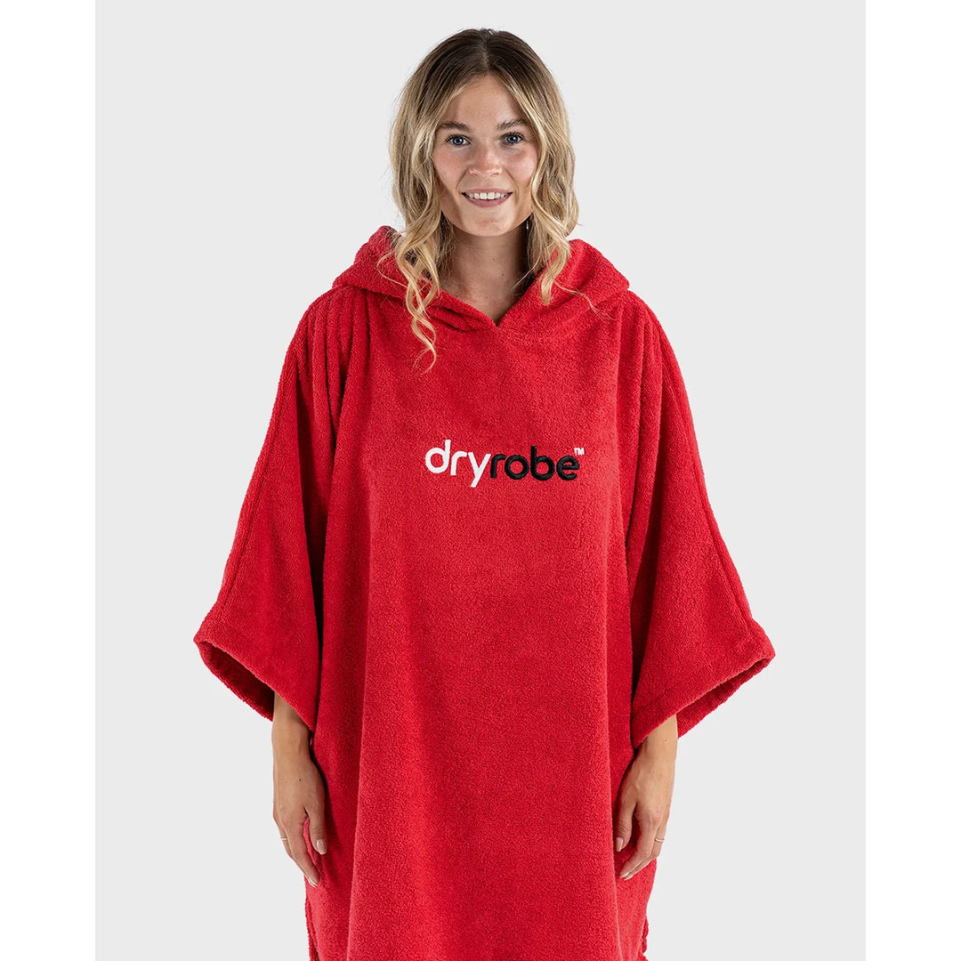 Person wearing a red 'dryrobe' poncho on a white background