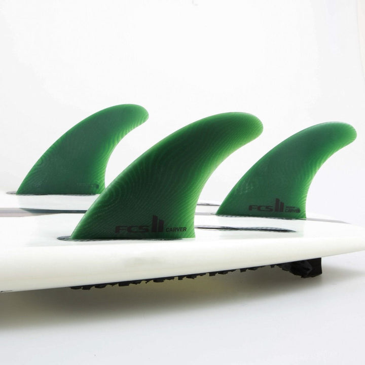 Close-up of a surfboard with green fins on a white background