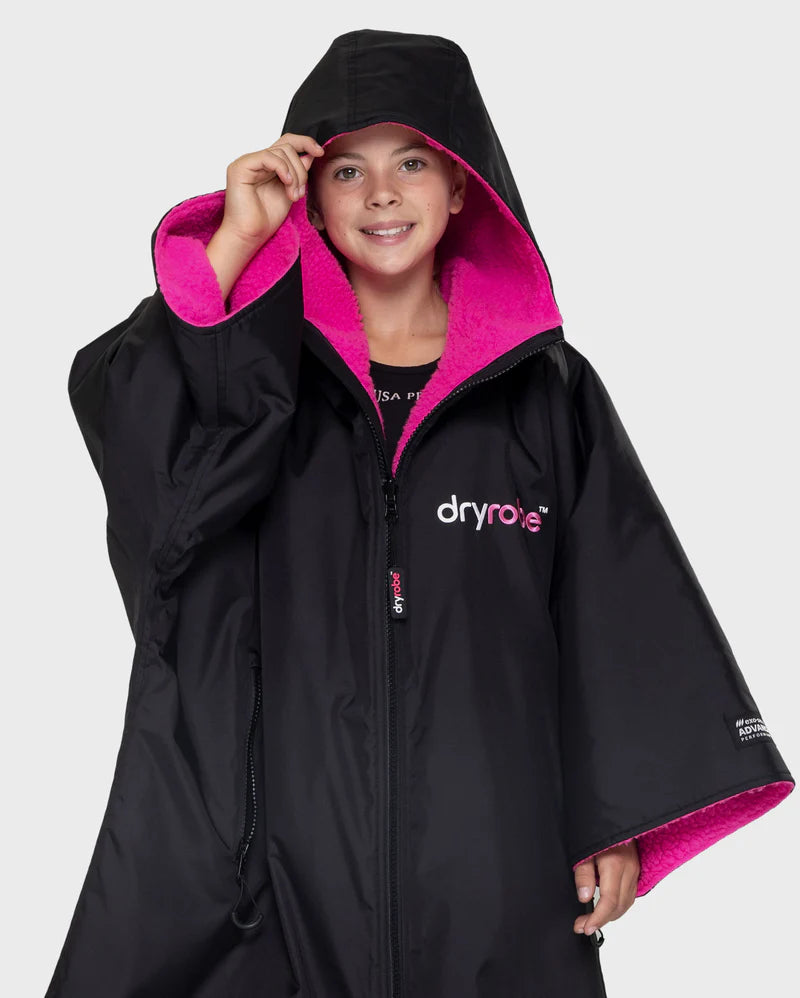 Person wearing a black raincoat with pink interior, featuring the Dryrobe brand.