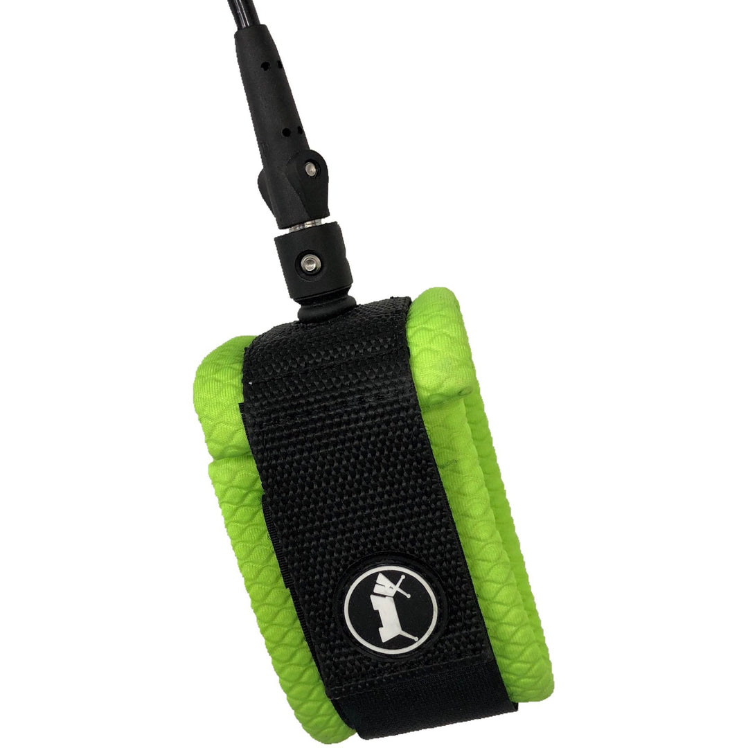 Close-up of green and black ankle strap of surfboard leash, with a white dog logo, on a white background.
